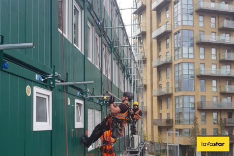Two workers rappelling down the side of a building