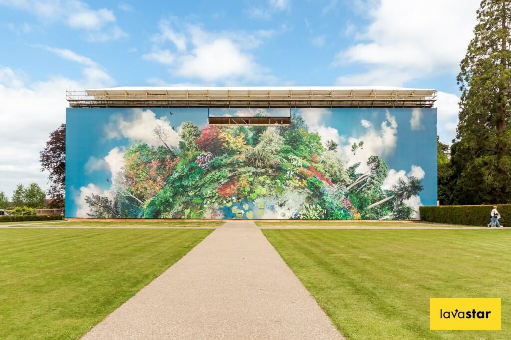 A building wrap depicting lush, colorful foliage against a blue sky