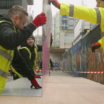 Folded printed hoarding panel being installed to promote a development