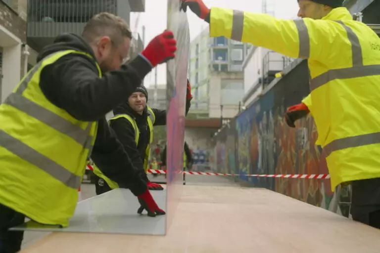 Folded printed hoarding panel being installed to promote a development