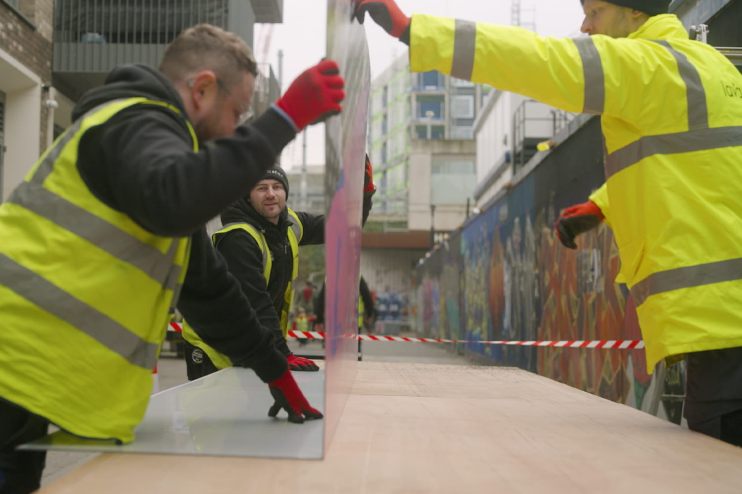 Folded printed hoarding panel being installed to promote a development